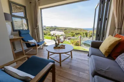 a living room with a couch and a table and a large window at Trewalder in St Merryn
