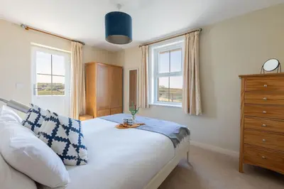 a bedroom with a bed with a dresser and two windows at Trewalder in St Merryn
