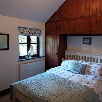 a bedroom with a bed and a window at The Granary -Trewen in Trewen