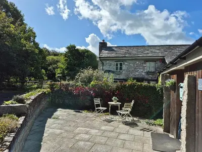 two chairs and a table in front of a house at The Granary -Trewen in Trewen