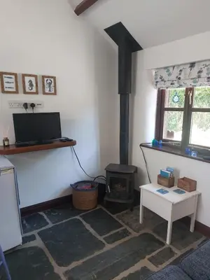 a living room with a fireplace and a stove at The Granary -Trewen in Trewen