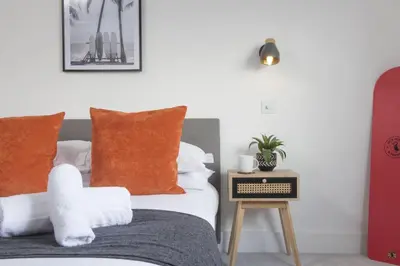 a bedroom with a bed with orange pillows and a table at Copper Tree in Newquay