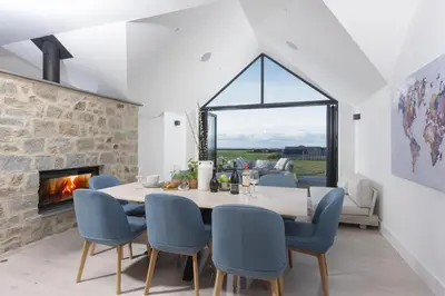 a dining room with a table and chairs and a fireplace at Copper Tree in Newquay