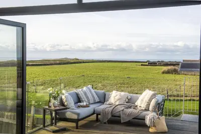 a living room with a couch and a view of a field at Copper Tree in Newquay