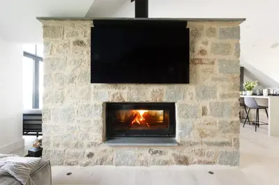 a stone fireplace with a television on top of it at Copper Tree in Newquay