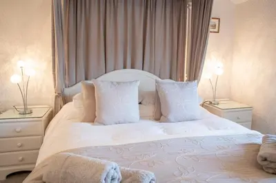 a white bed with white pillows and two night stands at Tregaddra Farm B&B in Helston