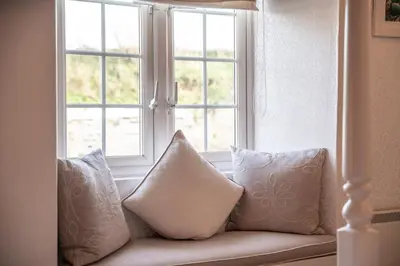 a couch with pillows in front of a window at Tregaddra Farm B&B in Helston