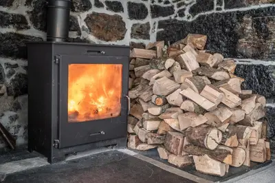 a pile of fire wood next to a stone fireplace at Tregaddra Farm B&B in Helston