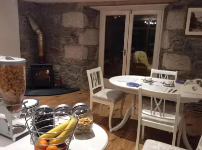 a kitchen with a table and chairs and a stove at Tregaddra Farm B&B in Helston