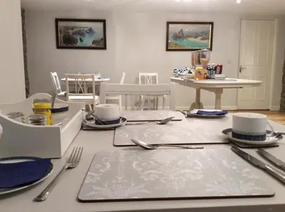 a dining room with a table with utensils on it at Tregaddra Farm B&B in Helston