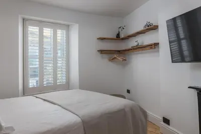 a white bedroom with a bed and a window at Premium 3BR Cottage Sauna EV Newquay in Newquay
