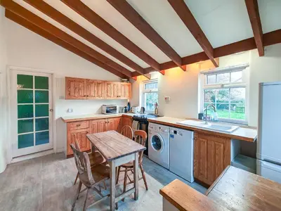 a kitchen with wooden cabinets and a table and a sink at 3 Bed in St. Merryn oc-l34453 in St Merryn