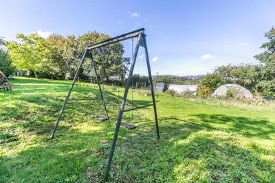 an old swing set in a grassy field at 1 Bed in St. Austell oc-b33396 in St Austell