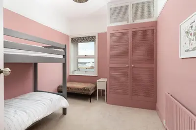 a bedroom with pink walls and a bunk bed at Spacious House nr Castle Beach Parking & Sauna in Falmouth