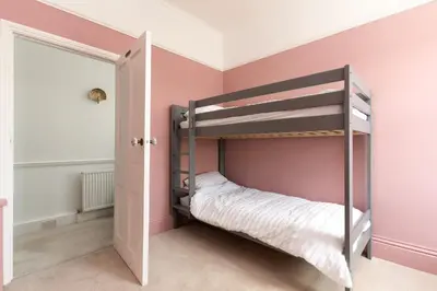 a bedroom with a bunk bed in a room with pink walls at Spacious House nr Castle Beach Parking & Sauna in Falmouth
