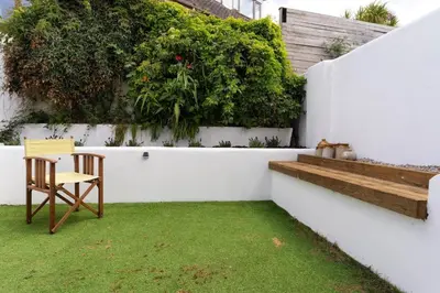 a white wall with a chair and a table in a yard at Spacious House nr Castle Beach Parking & Sauna in Falmouth