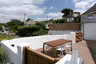 a balcony with a wooden table and chairs on it at Spacious House nr Castle Beach Parking & Sauna in Falmouth