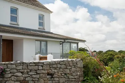 a white house with a stone wall at Spacious House nr Castle Beach Parking & Sauna in Falmouth