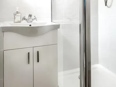 a white bathroom with a sink and a shower at Kenwith Cottage in Looe