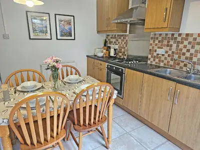 a kitchen with a table with chairs and a sink at Kenwith Cottage in Looe