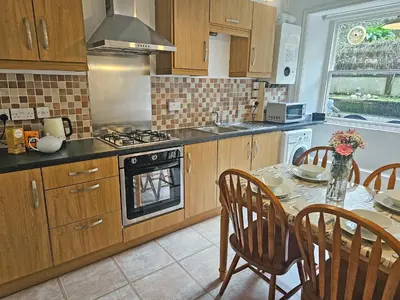 a kitchen with a table and a stove top oven at Kenwith Cottage in Looe