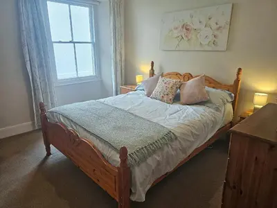 a bedroom with a wooden bed with pillows and a window at Kenwith Cottage in Looe