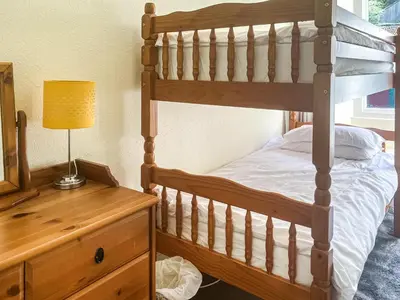 a bedroom with a bunk bed with a lamp on a dresser at Kenwith Cottage in Looe