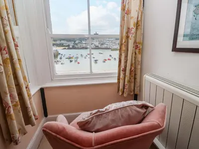 a chair in front of a window with a view of a beach at Pelican Cottage in St Ives