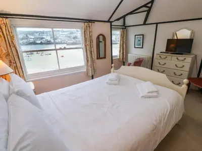a bedroom with a large white bed and a window at Pelican Cottage in St Ives