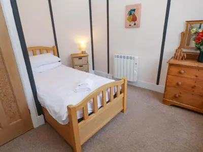 a small bedroom with a wooden bed and a dresser at Pelican Cottage in St Ives