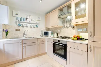 a kitchen with white cabinets and a bowl of fruit on the counter at 2 Bed in Padstow oc-p00337 in Padstow