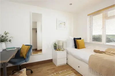 a bedroom with a desk and a bed with yellow pillows at Ocean View, Mawgan Porth - Sea Views - Hot Tub - Free Parking & WiFi in Mawgan Porth