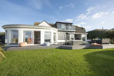 a large house with a lawn in front of it at Ocean View, Mawgan Porth - Sea Views - Hot Tub - Free Parking & WiFi in Mawgan Porth