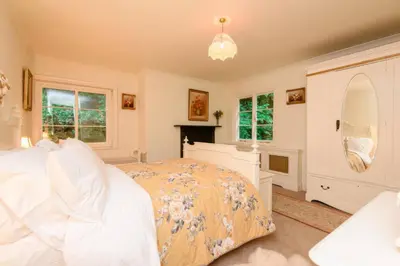 a bedroom with a bed and a fireplace and windows at Ladye Park in Liskeard