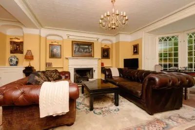 a living room with leather furniture and a fireplace at Ladye Park in Liskeard