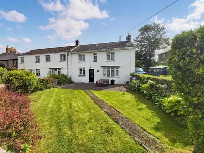 a white house with a lawn in front of it at Orchard Cottage in Penzance