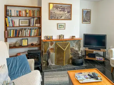 a living room with a fireplace and a tv at Orchard Cottage in Penzance