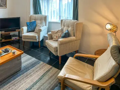 a living room with two chairs and a tv at Orchard Cottage in Penzance