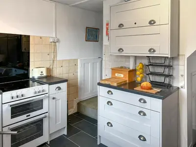 a kitchen with white cabinets and a counter top at Orchard Cottage in Penzance