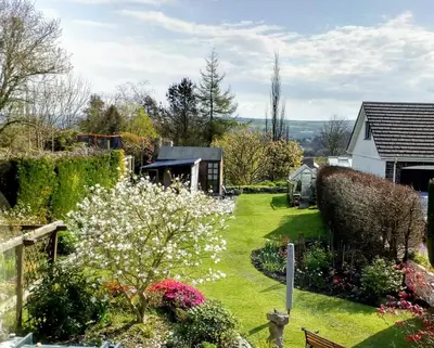 a garden with white flowers and a house at The White Cottage B&B in Saint Teath