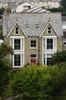 a brick house with a red door at Cliftons Guest House in Truro