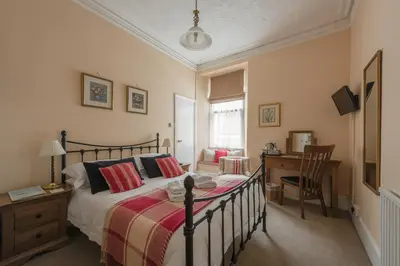 a bedroom with a bed with a desk and a chair at Cliftons Guest House in Truro