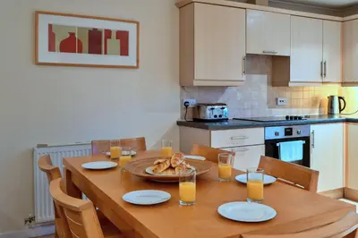 a kitchen with a wooden table with glasses of orange juice at Finest Retreats - 2 Chy Lowen in Newquay