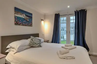 a bedroom with a large white bed with blue curtains at Finest Retreats - Atlantic 55 in Newquay