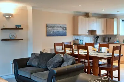 a living room and kitchen with a couch and a table at Finest Retreats - Atlantic 55 in Newquay