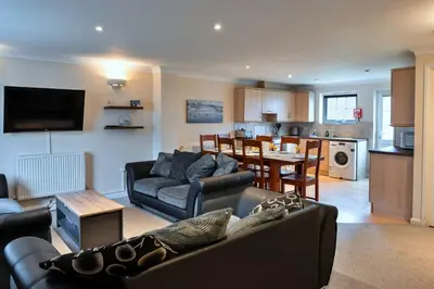 a living room with a couch and a table and a kitchen at Finest Retreats - Atlantic 55 in Newquay