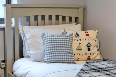 a bedroom with a bed with pillows and a crib at Finest Retreats - Pobbles Place in Fowey
