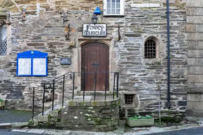 a stone building with a wooden door with a sign on it at Finest Retreats - Pobbles Place in Fowey