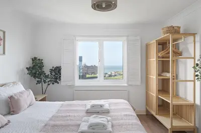 a white bedroom with a large bed and a window at Apartment Sea Views & Parking Walk to Fistral in Newquay