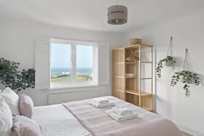 a white bedroom with a bed with towels on it at Apartment Sea Views & Parking Walk to Fistral in Newquay